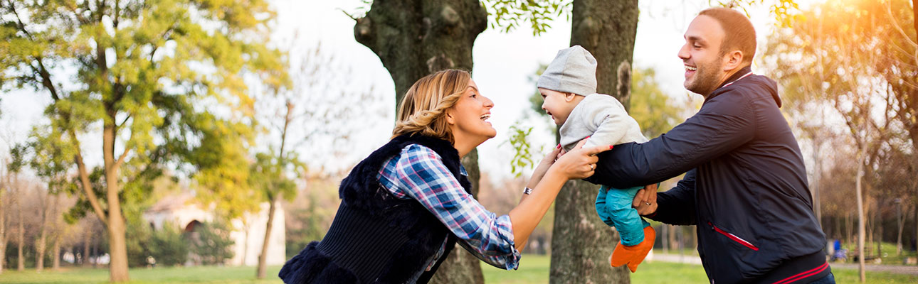 Young parents playing outside with baby