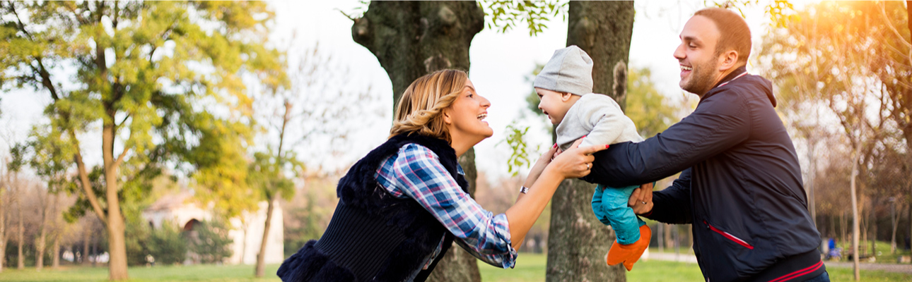 Young parents playing outside with baby