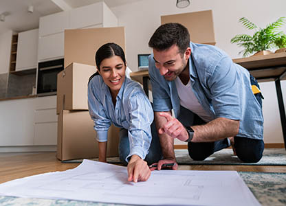 Couple reviewing blueprints on living room floor